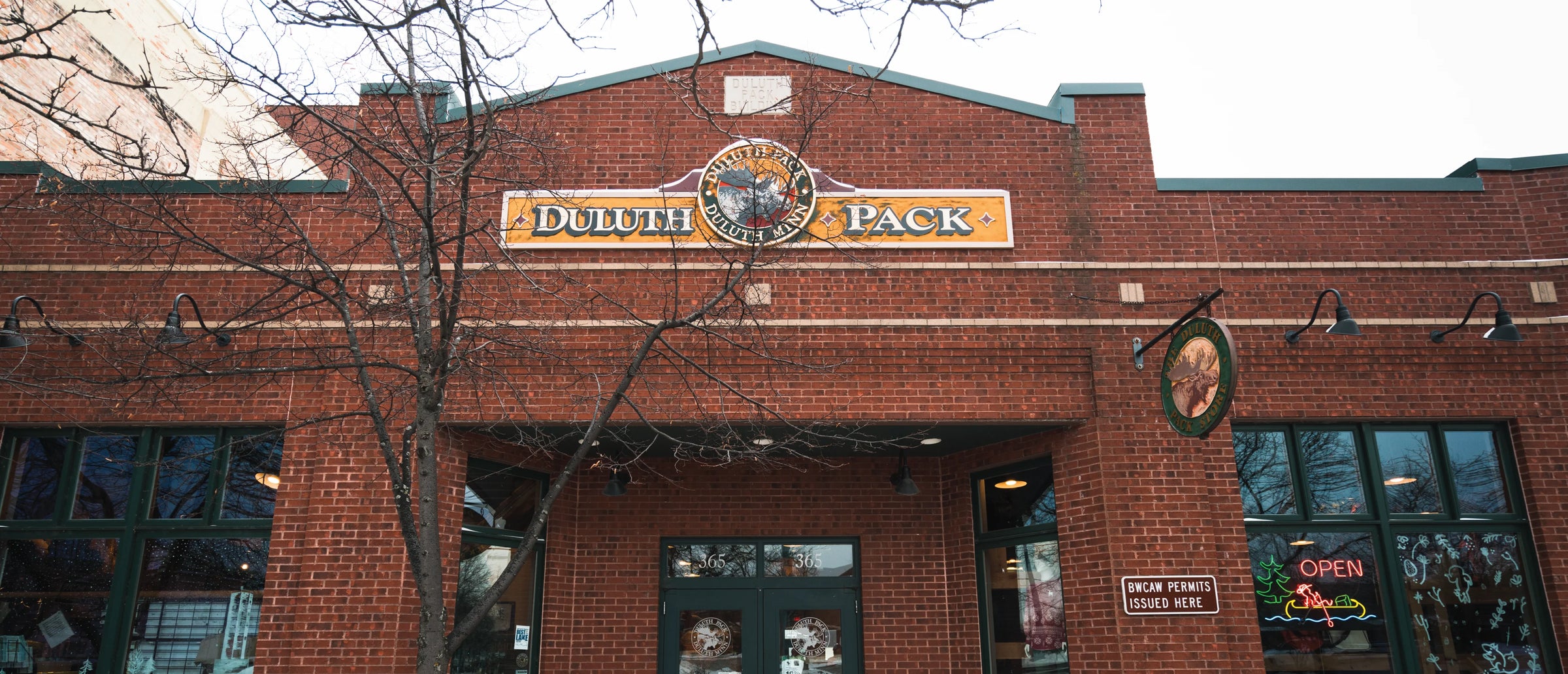 Historic Duluth Pack storefront with vintage brick exterior, classic signage, and large windows, reflecting a heritage of handmade outdoor canvas and leather gear since 1882.