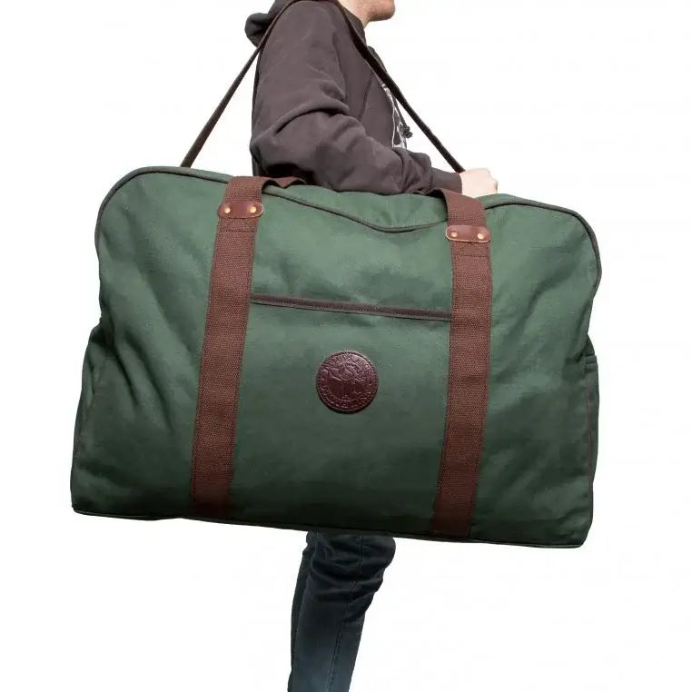 Large Safari Duffel In Olive Drab Green Being Carried By A Man On A Plain White Background