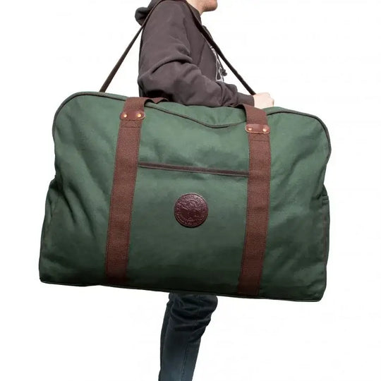 Large Safari Duffel In Olive Drab Green Being Carried By A Man On A Plain White Background